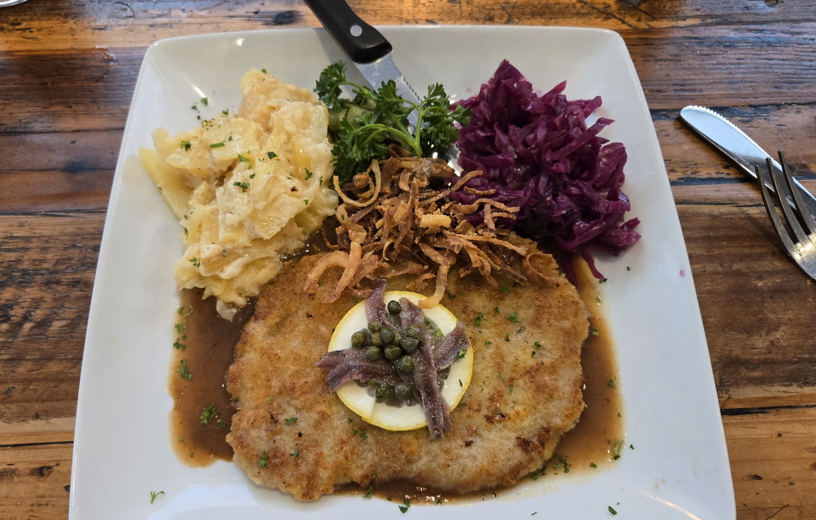Breaded plated entree with potatoes, red cabbage, fried onions, and garnish