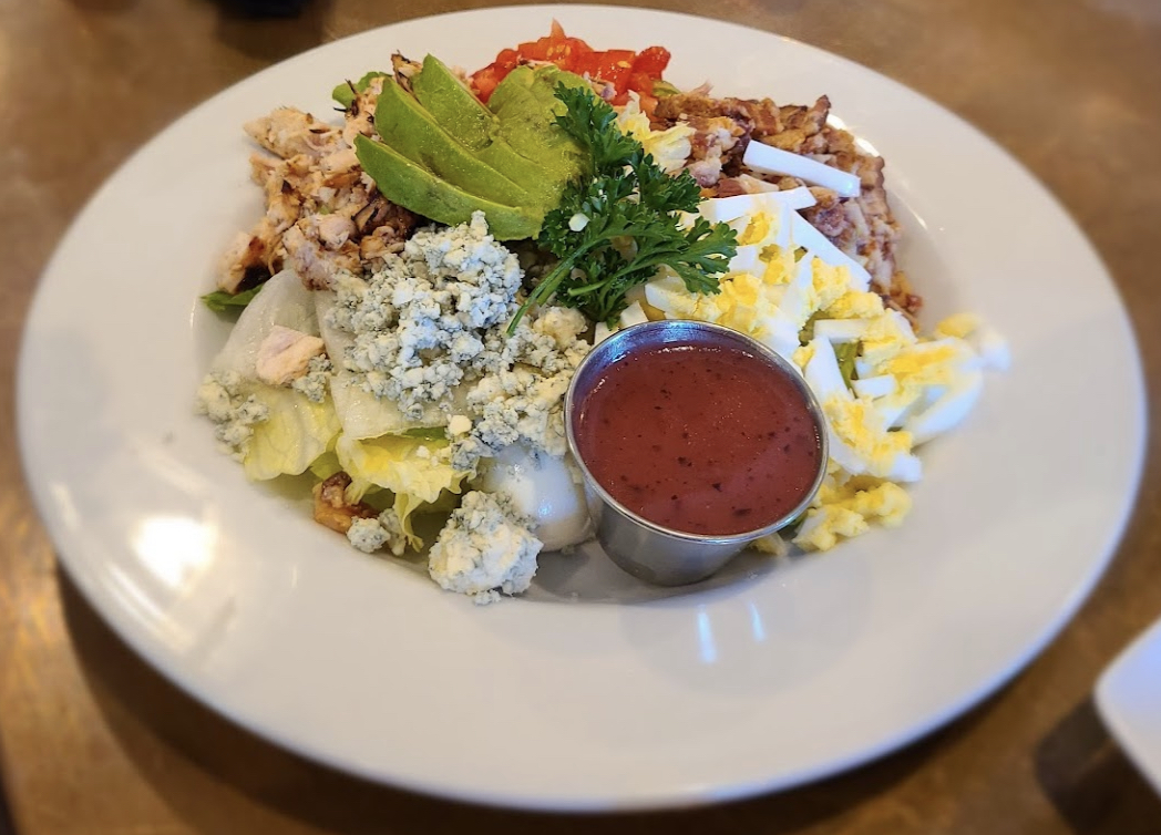 Composed salad with avocado, chopped egg, tomatoes, greens, and dressing