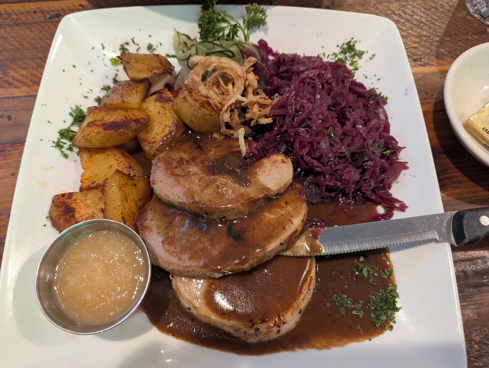 Plated meal with sliced meat, gravy, red cabbage, potatoes, and fried onions